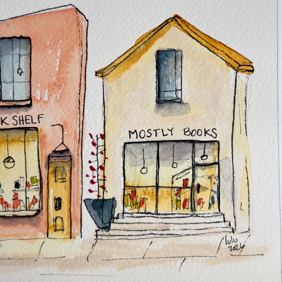 A watercolor art print depicting four stone bookstore buildings, presented with a wide white mat board against a neutral gray background.