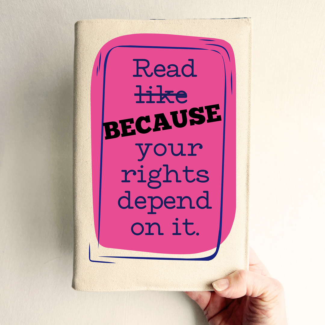 Canvas, reusable book cover in linen, with the words,  'Read like (because) your rights depend on it' in navy lettering on a pink box design.