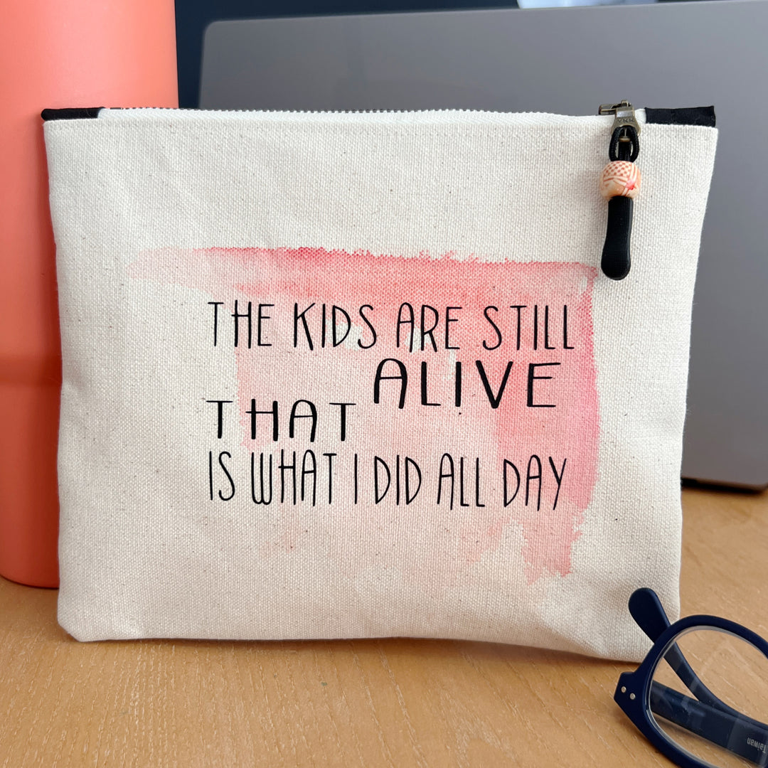 a square canvas zip bag with pink watercolor swash and the words, "the kids are still alive. THAT is what I did all day." in black lettering