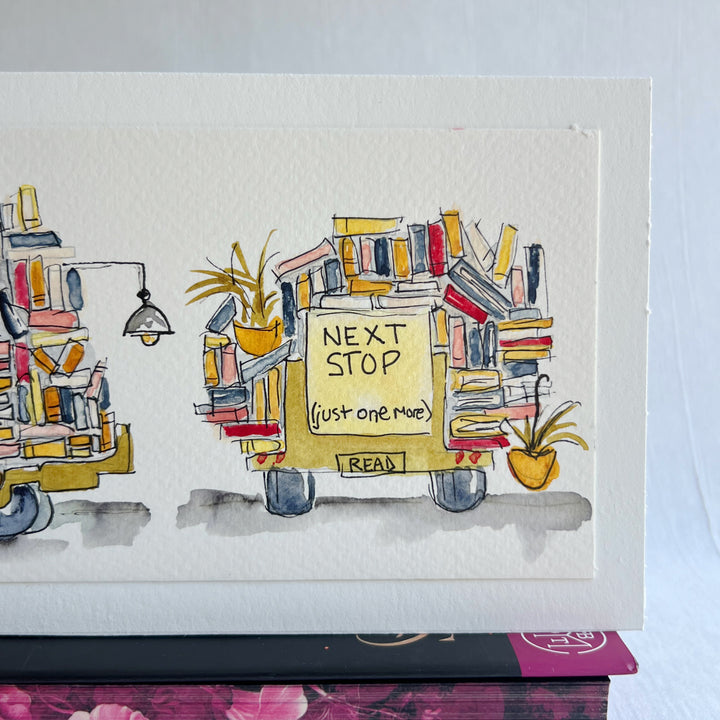 A rectangular watercolor painting of two yellow book trucks stacked and overloaded with books and potted plants, plus a wonky book light, all displayed on top of a decorative pink floral book  against a white background.
