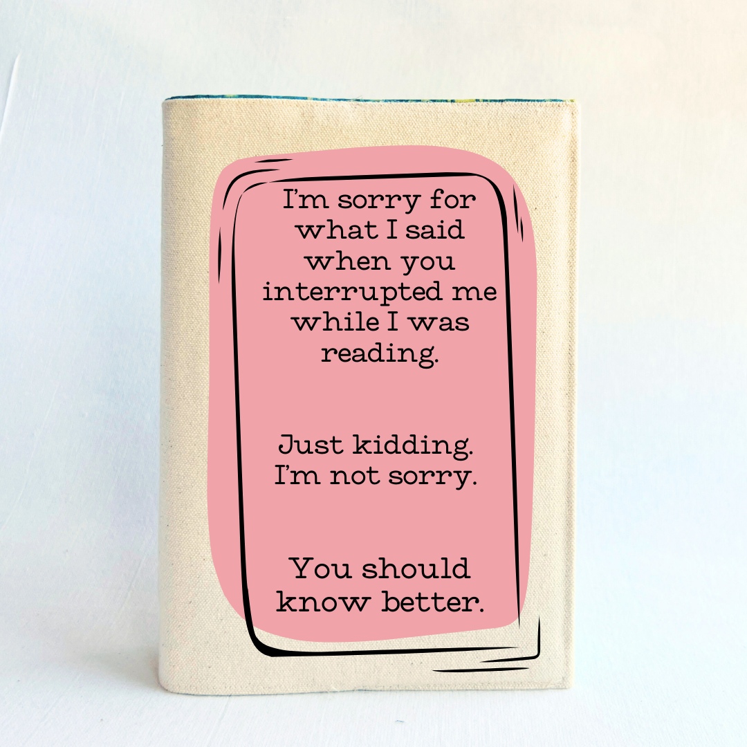 a book covered with a linen-color reusable, readjustable book cover.  A pink square background has the words, 'I'm sorry for what I said when you interrupted me while I was reading.  Just kidding. I'm not sorry. You should know better.' in black lettering.