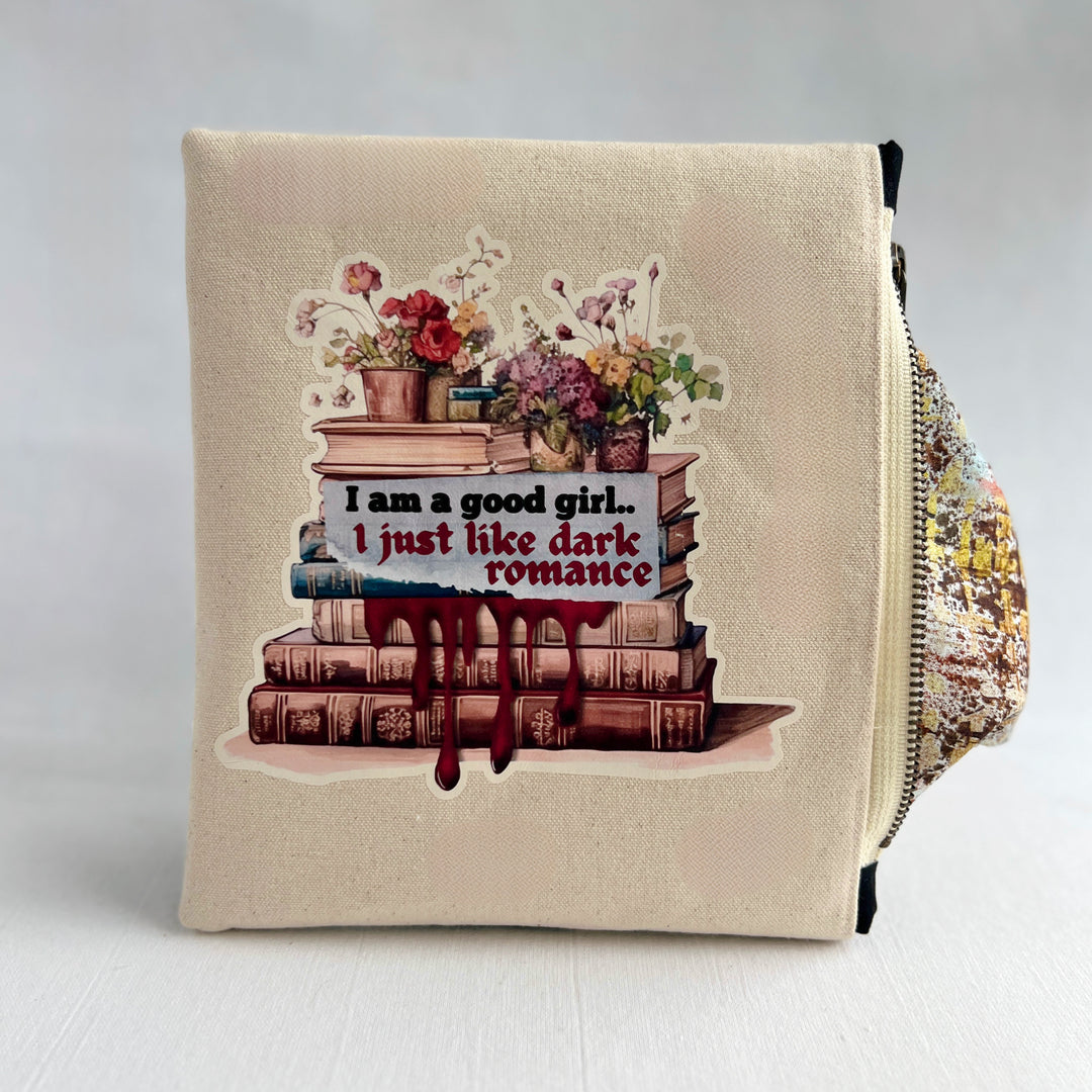 square canvas zip bag with lining and a design of stacked books, flowers, and the words, "I am a good girl..I just like dark romance."