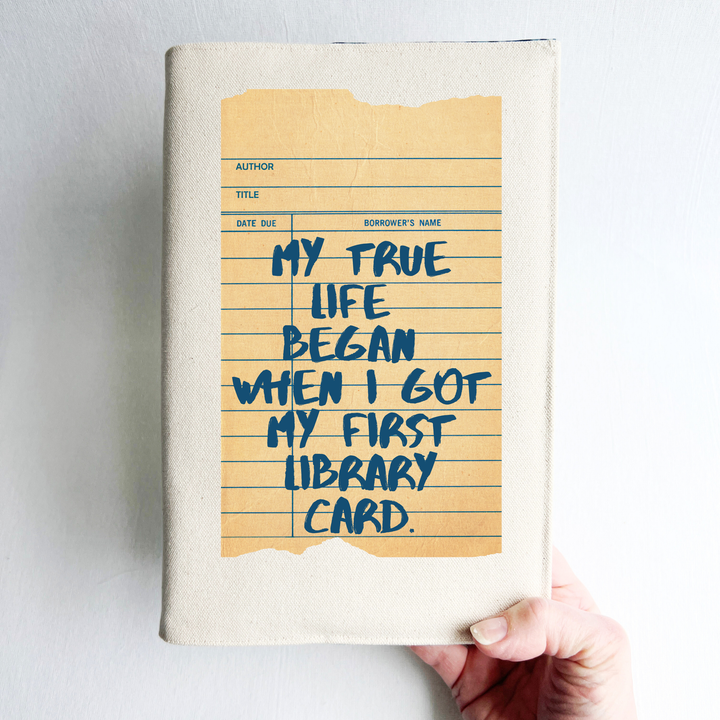 Canvas, reusable book covers in linen, with the words, 'My true life began when I got my first library card' printed on a vintage-style library check out card design.
