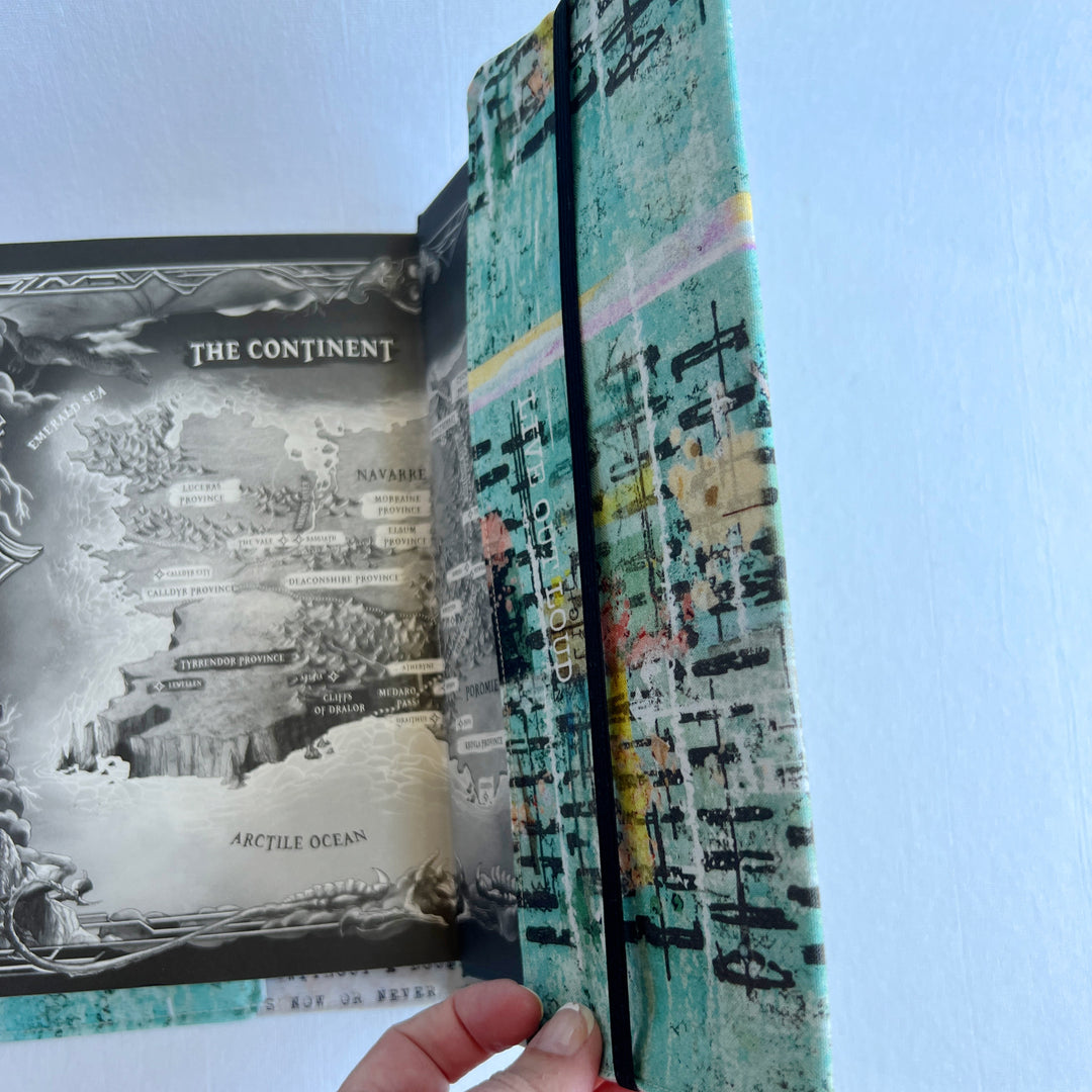 the inside back cover of a book covered in a vibrant blue green fabric reusable book cover with the words, 'live out loud' printed on the top.