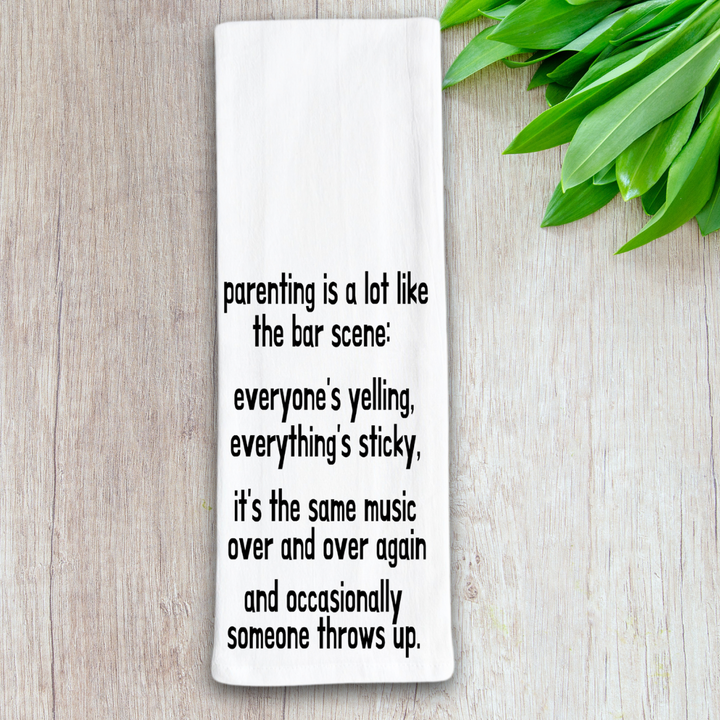 rectangular white kitchen towel with the words, parenting is lot like the bar scene: everyone's yelling, everything's sticky, it's the same music over and over again and occasionally someone throws up.
