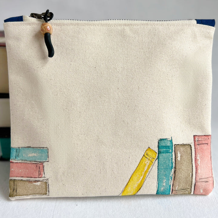 An off-white canvas zippered pouch with original watercolor painted colorful books along the bottom edge.