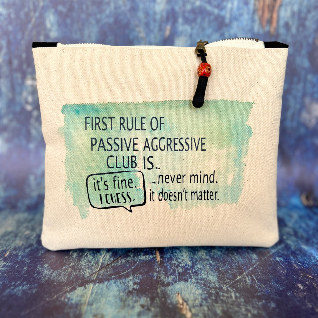 a canvas zip bag with blue watercolor painting and the words, "First rule of passive aggressive club is..never mind. it doesn't matter. it's fine. I guess."