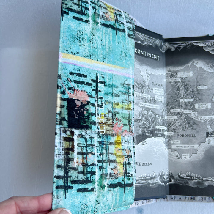the inside front cover of a book covered in a vibrant blue green fabric reusable book cover with the words, 'live out loud' printed on the top.