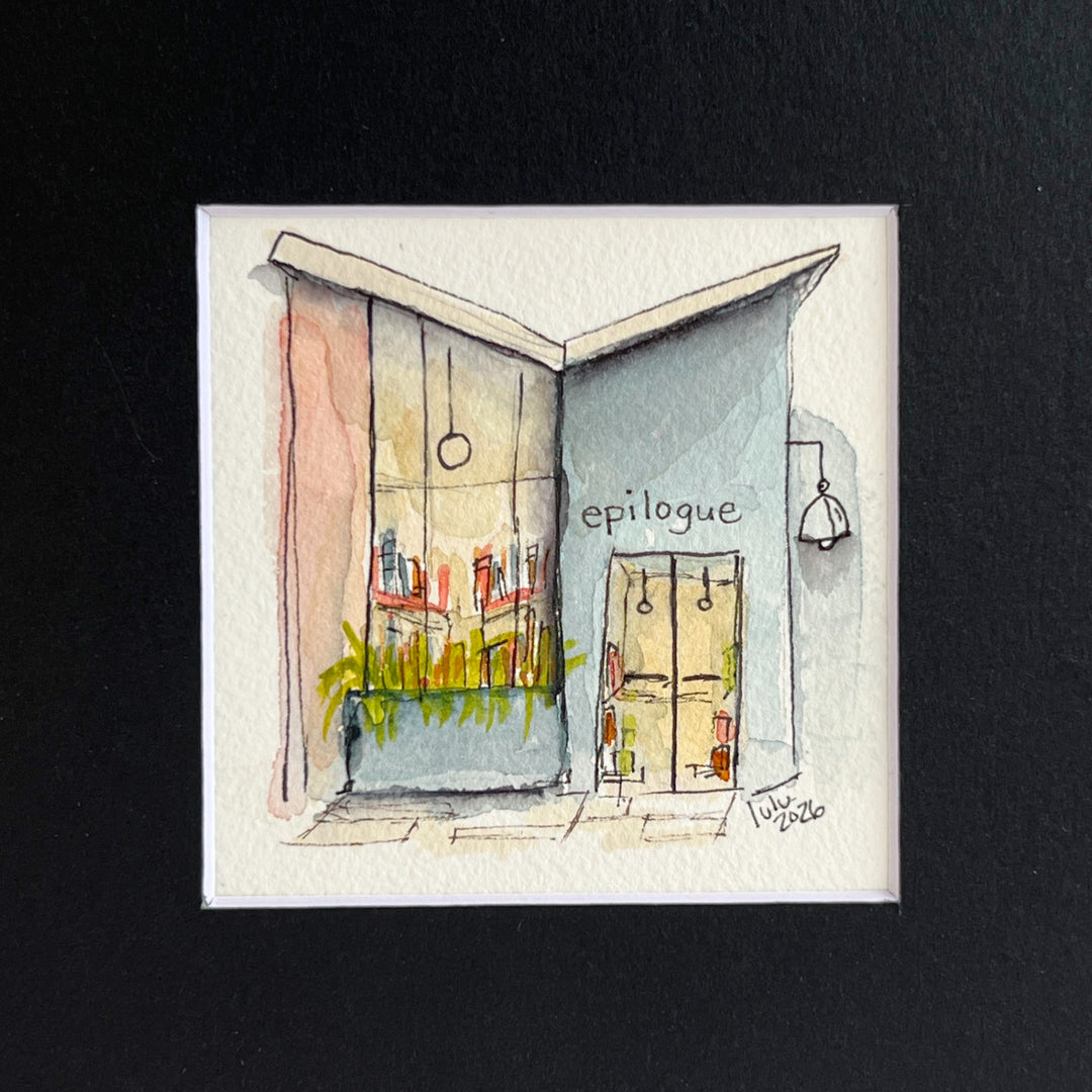 A matted watercolor painting of a cozy midcentury modern bookshop storefront with the store name  'EPILOGUE' above a window filled with books, a glass door, and a hanging lamp, shown on a white mat and white frame.