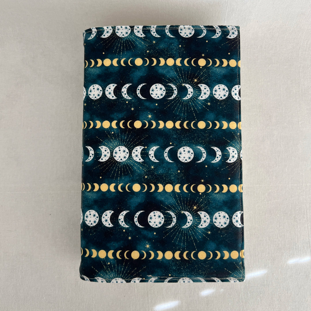 a rectangular book cover made of deep blue fabric with white and yellow stars and moons