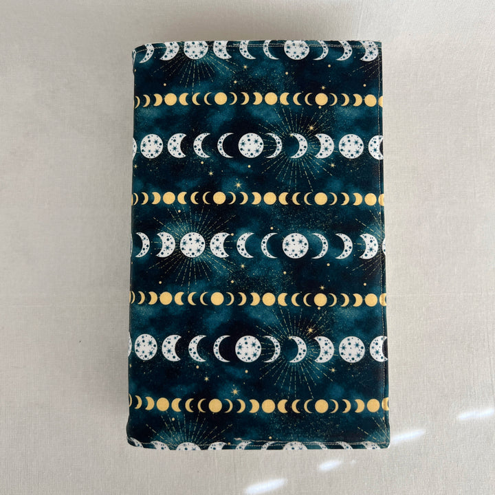 a rectangular book cover made of deep blue fabric with white and yellow stars and moons