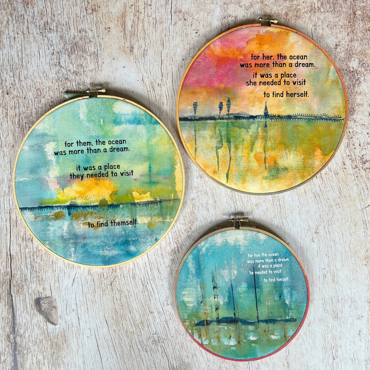 a collection of colorful hoop art pieces. Large painted hoop art pieces, with rose pinks, bright blues, fresh greens and vibrant yellows, stitched with a rickety pier and finished with the words, for here, the ocean was more than a dream. it was a place she/he/them needed to visit to find herself/himself/themself..