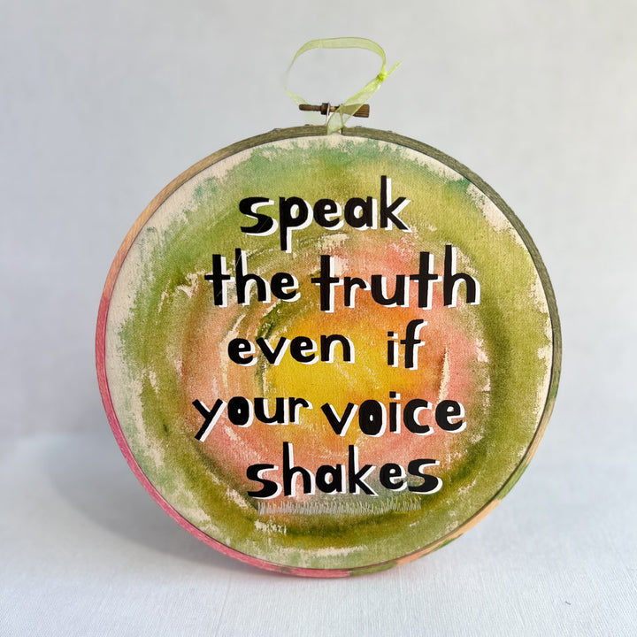eight inch painted wooden embroidery hoop with canvas, painted with greens pinks and yellows, with the words, speak the truth, even if your voice shakes.