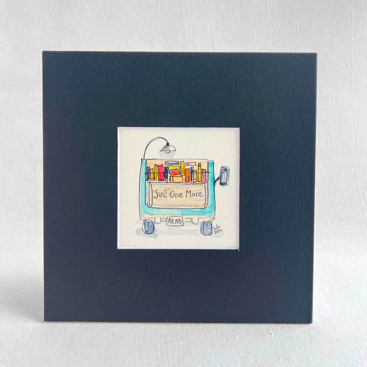 A square original watercolor art print depicting the back end of a blue pickup truck loaded with colorful books and a wonky reading light, with the words, "Just One More' and a license plate with the word 'Read'