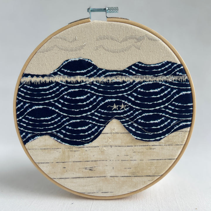 embroidery hoop art piece stitched fabric in shades of blue and yellow