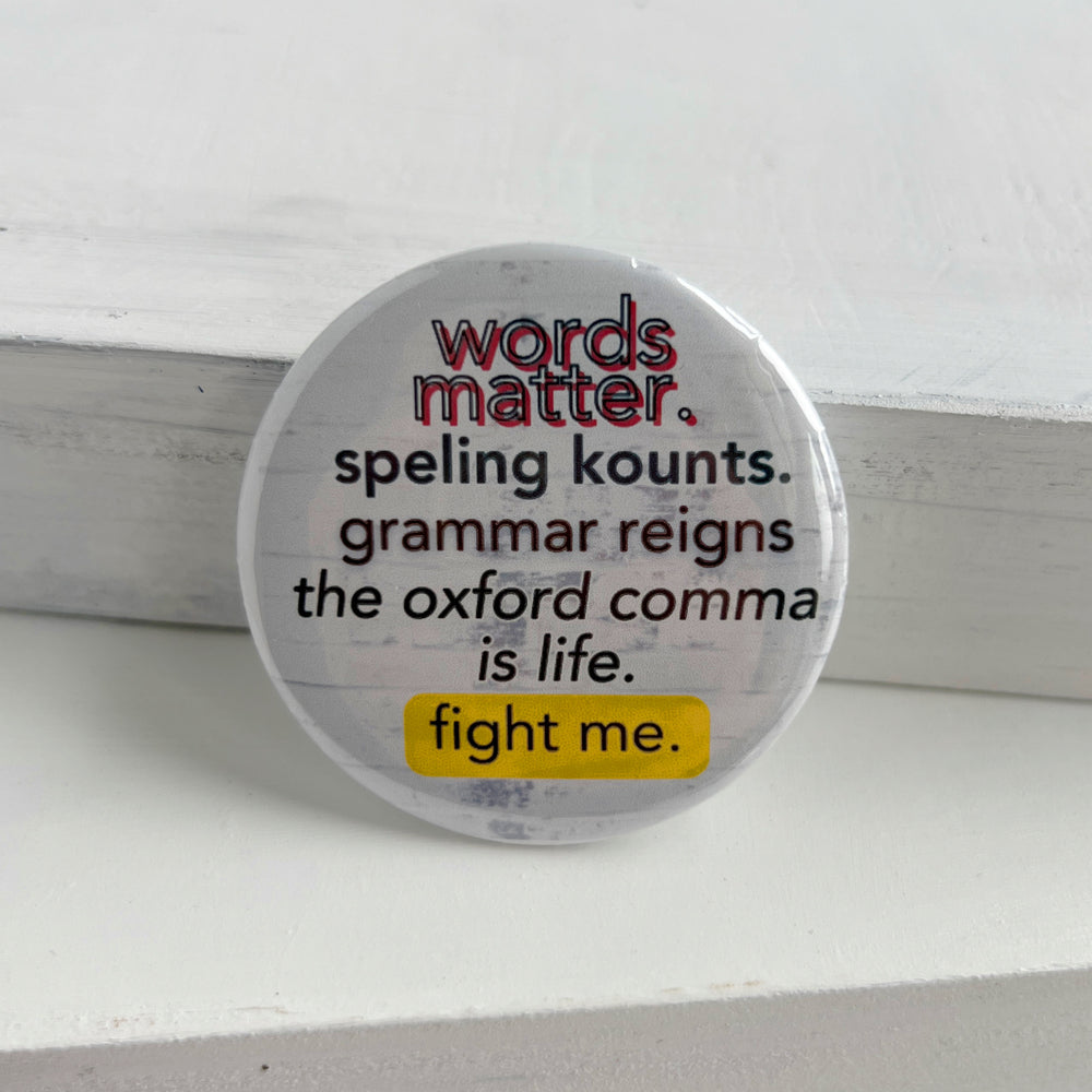 a round pin back button with a white background and the words, "words matter. speling kounts. grammar reins. the oxford comma is life. fight me."