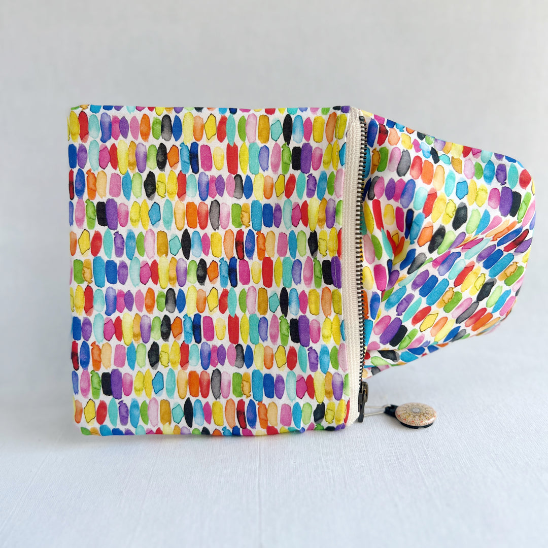 padded canvas zip bag with watercolor brushstrokes, plus a colorful zipper pull and lining