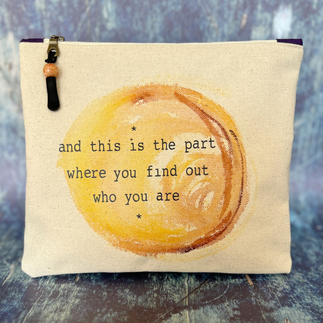 canvas zip bag measuring 9x7 inches, with a watercolor paint swash and the words, "and this is the part where you find out who you are" in black lettering.