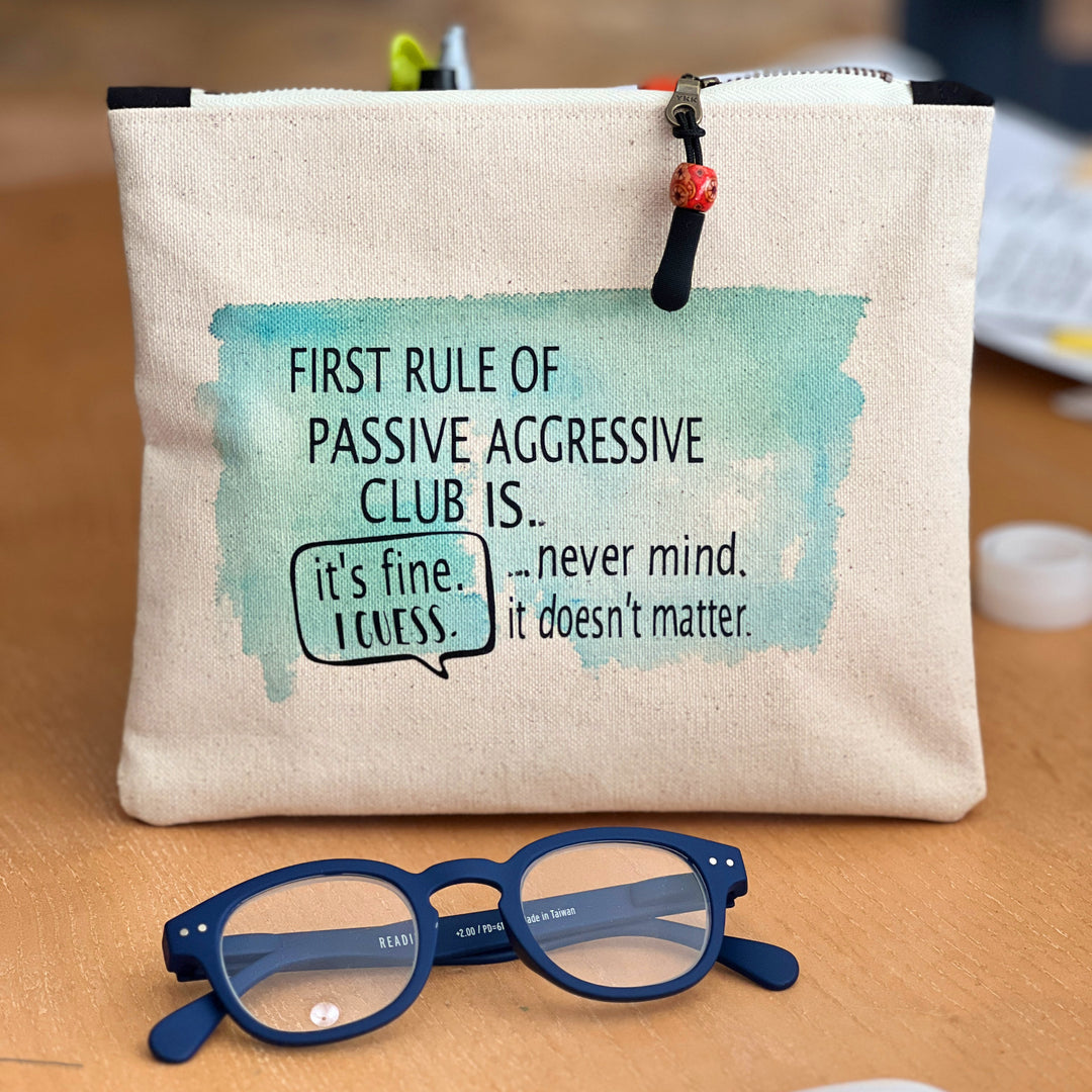 a canvas zip bag with blue watercolor painting and the words, "First rule of passive aggressive club is..never mind. it doesn't matter. it's fine. I guess."