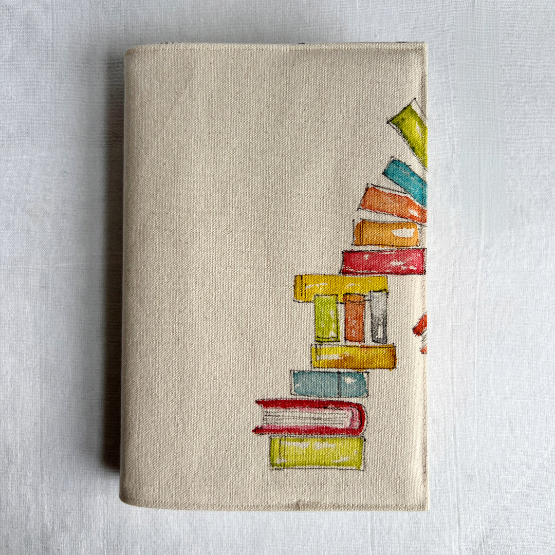 A canvas linen book cover featuring a hand-painted stack of colorful books on the right side.