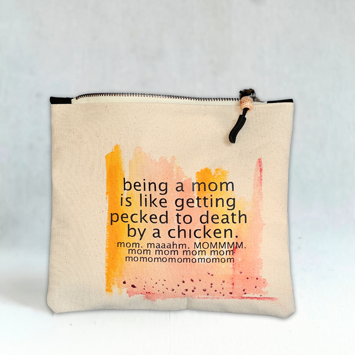 a square canvas zip bag with the words, being a mom is like getting pecked to death by a chicken.