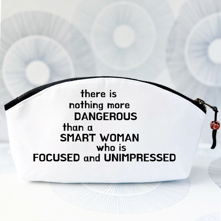 white canvas bag with curvy top, black zipper and the words, there is nothing more dangerous than a smart woman who is focused and unimpressed