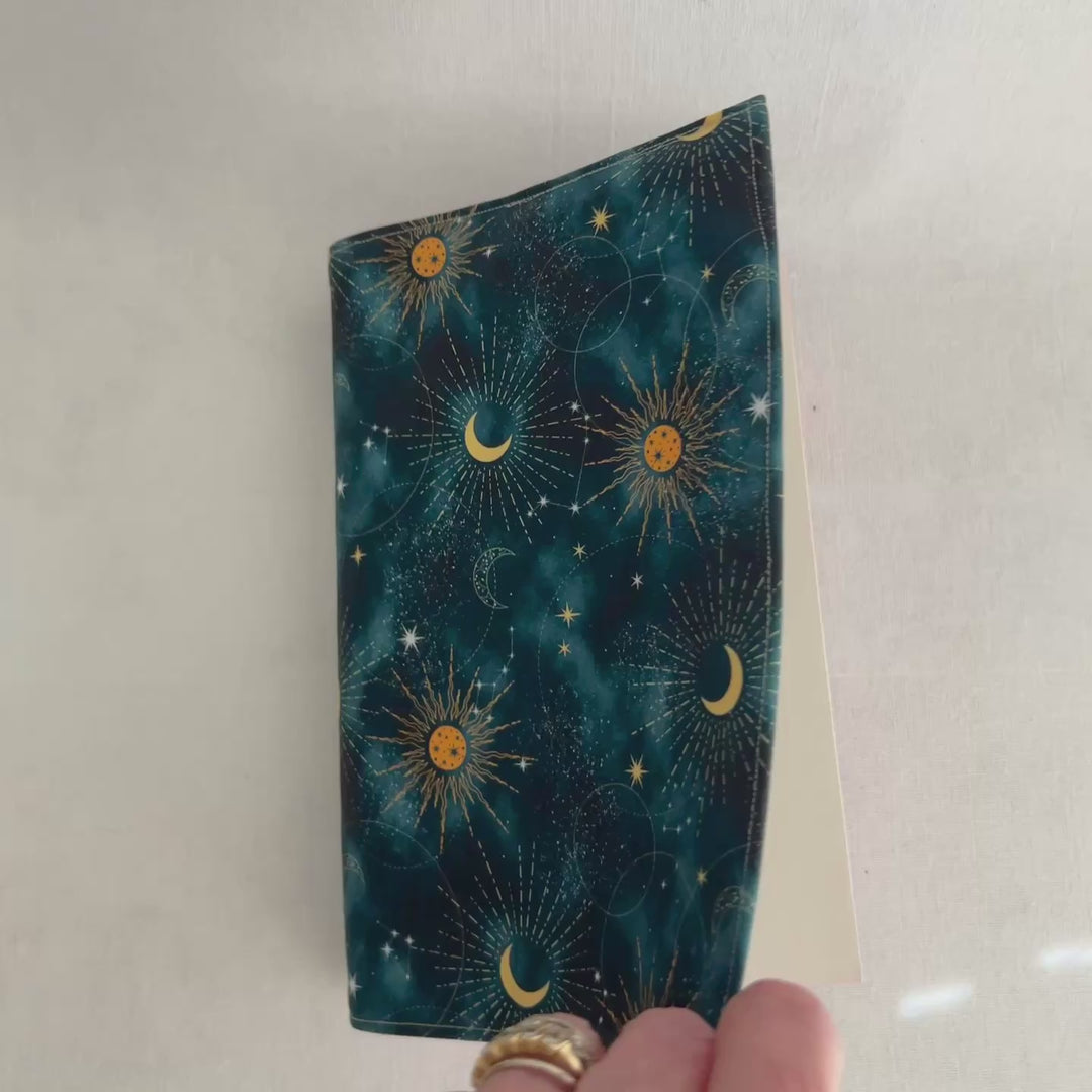 rectangular fabric batik book cover, with a celestial pattern of deep blue covered with scattered suns and moons