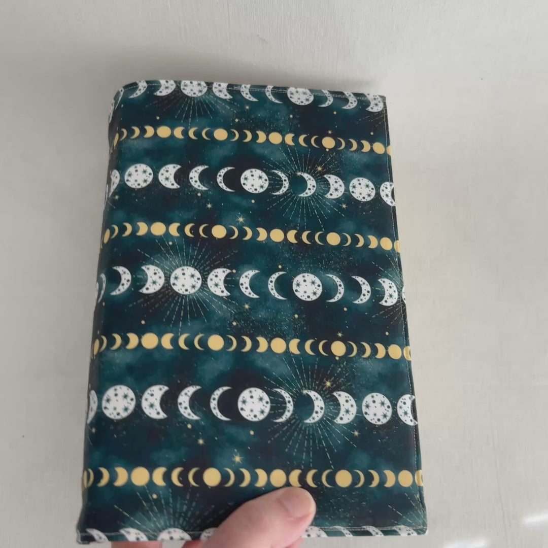 a rectangular book cover made of deep blue fabric with white and yellow stars and moons