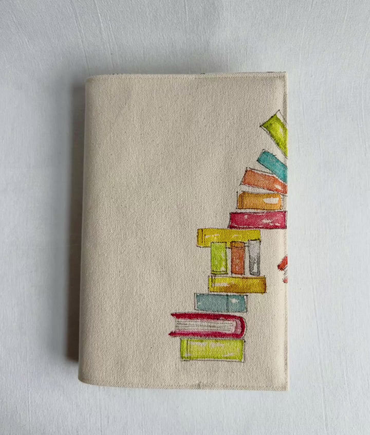 a video of a canvas linen book cover featuring a hand-painted stack of colorful books on the right side.