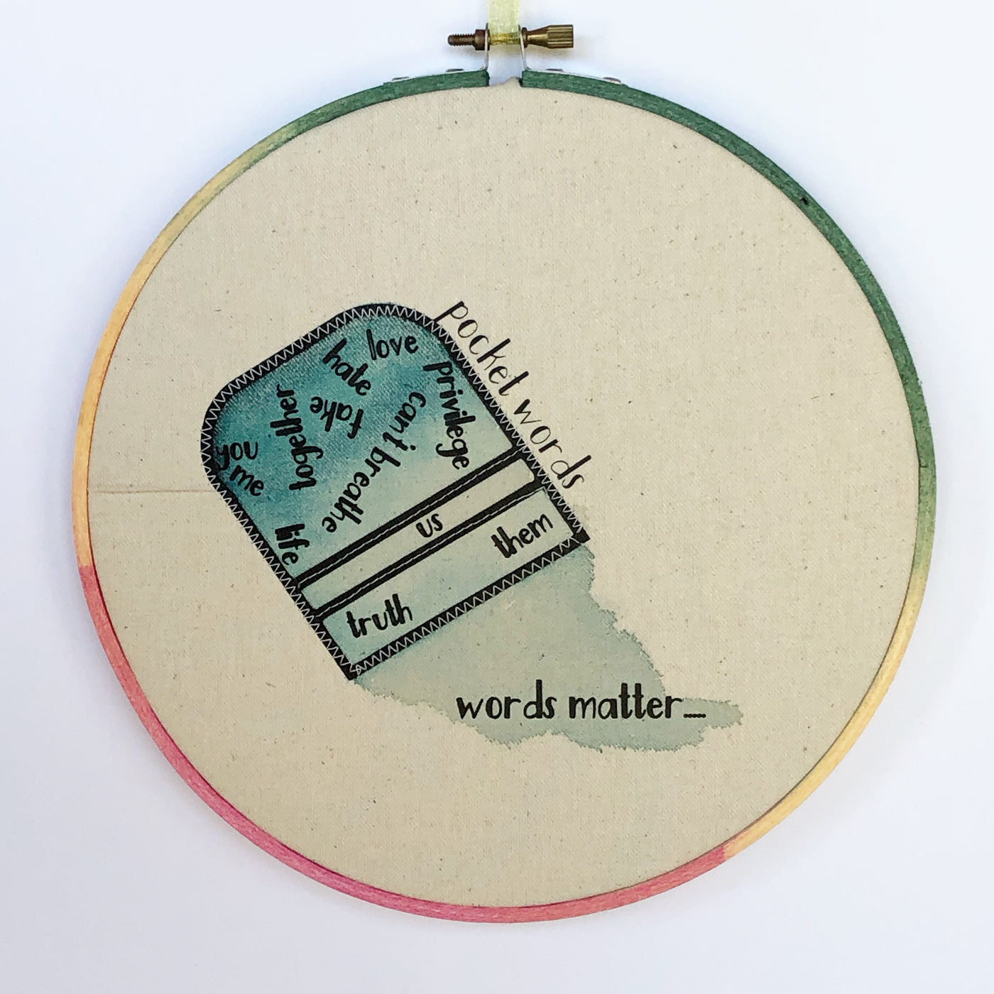 a canvas hoop art piece with a blue painted upside down pocket and the words, "you, me life together love fake, hate, privilege, can't breathe, truth, us, them and words matter.." 