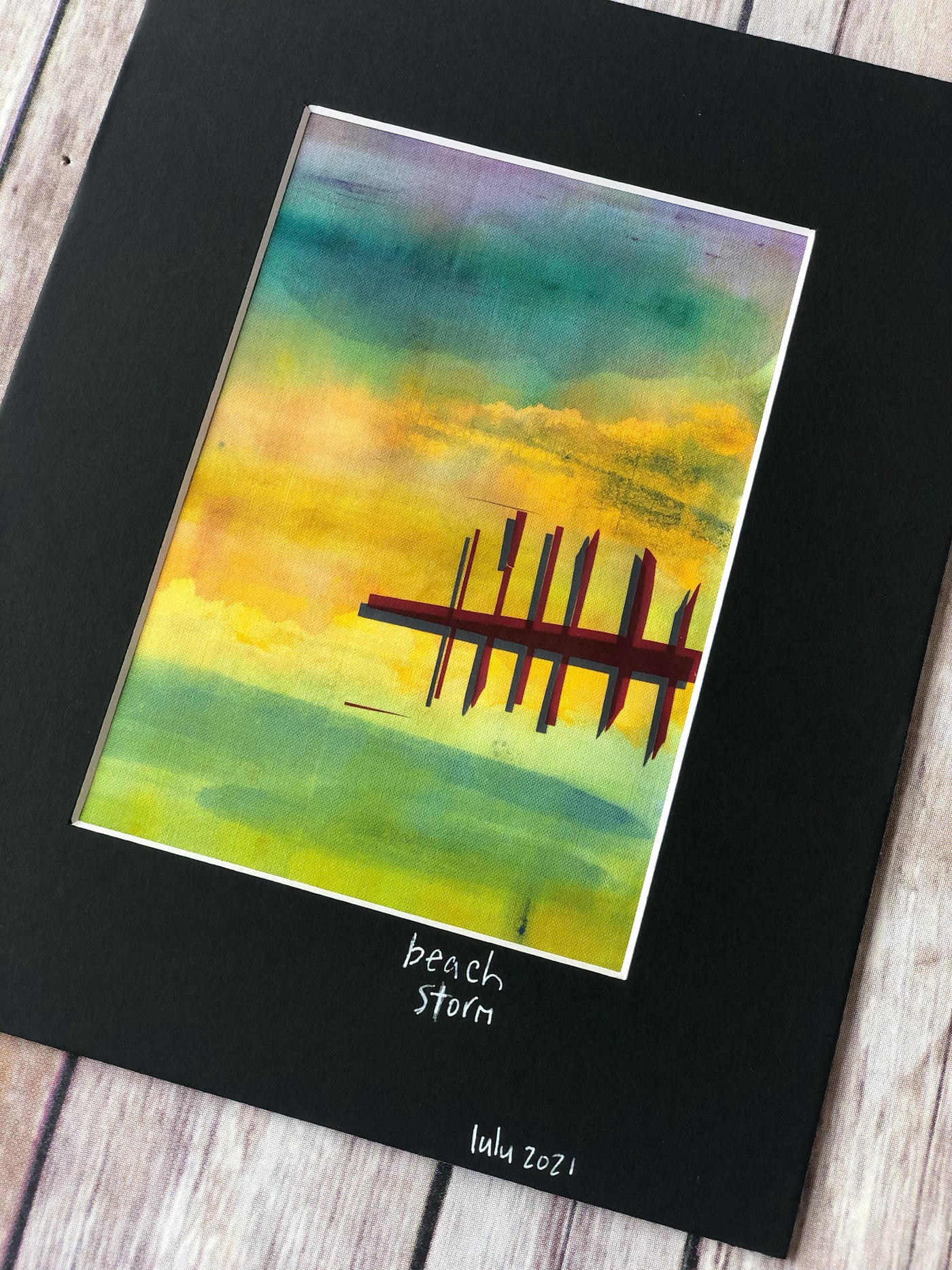 fabric art piece with blues, greens and purple paints, layered with a vinyl depicting a pier