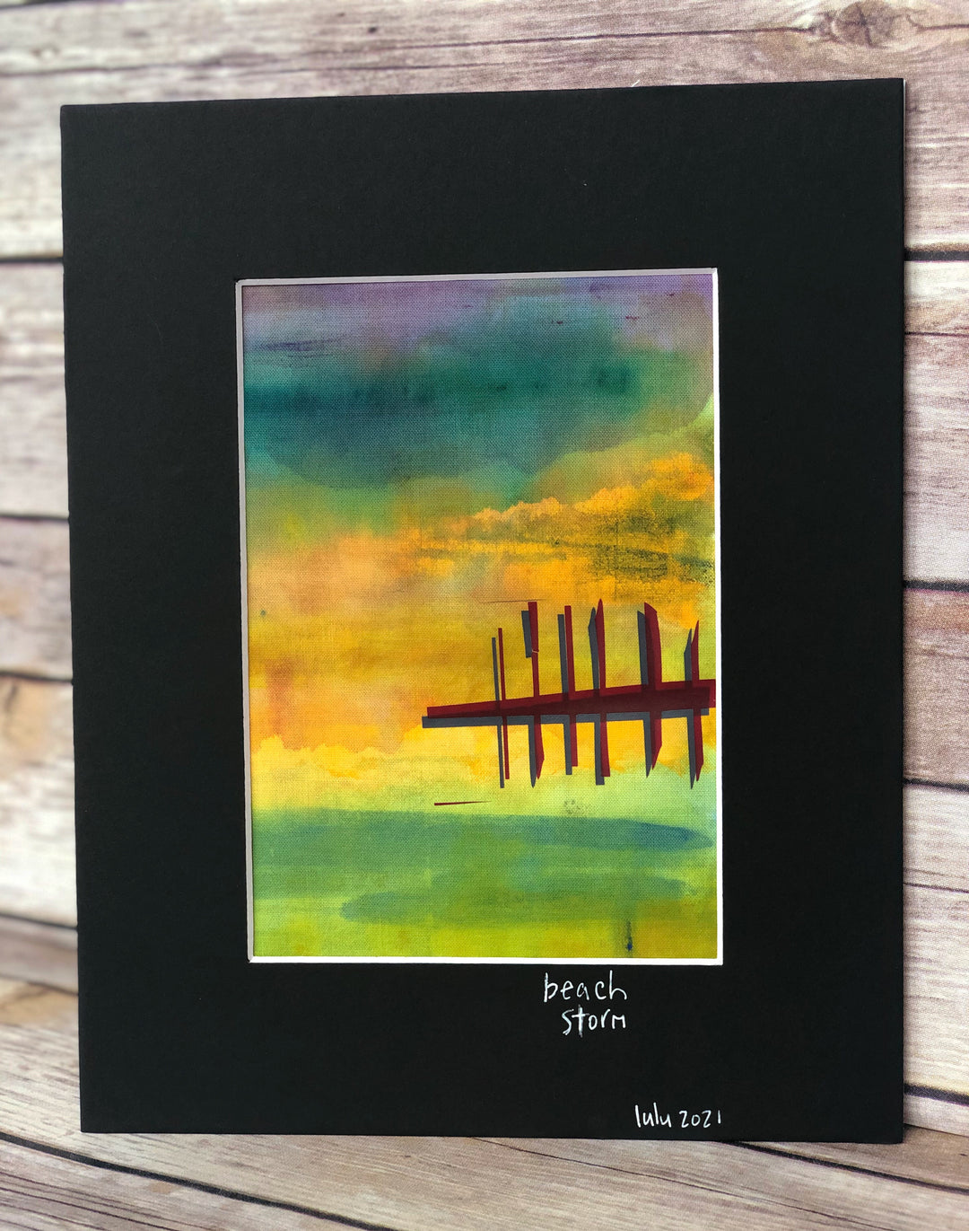 fabric art piece with blues, greens and purple paints, layered with a vinyl depicting a pier