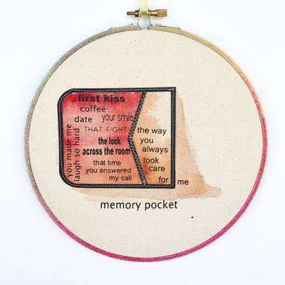 a round wooden painted hoop with canvas, a painted red pocket on its side with the words spilling out...memory pocket, first kiss, coffee date, your smile, the look across the room, that time you answered my call, you always made me laugh so har, the way you always took care for me.