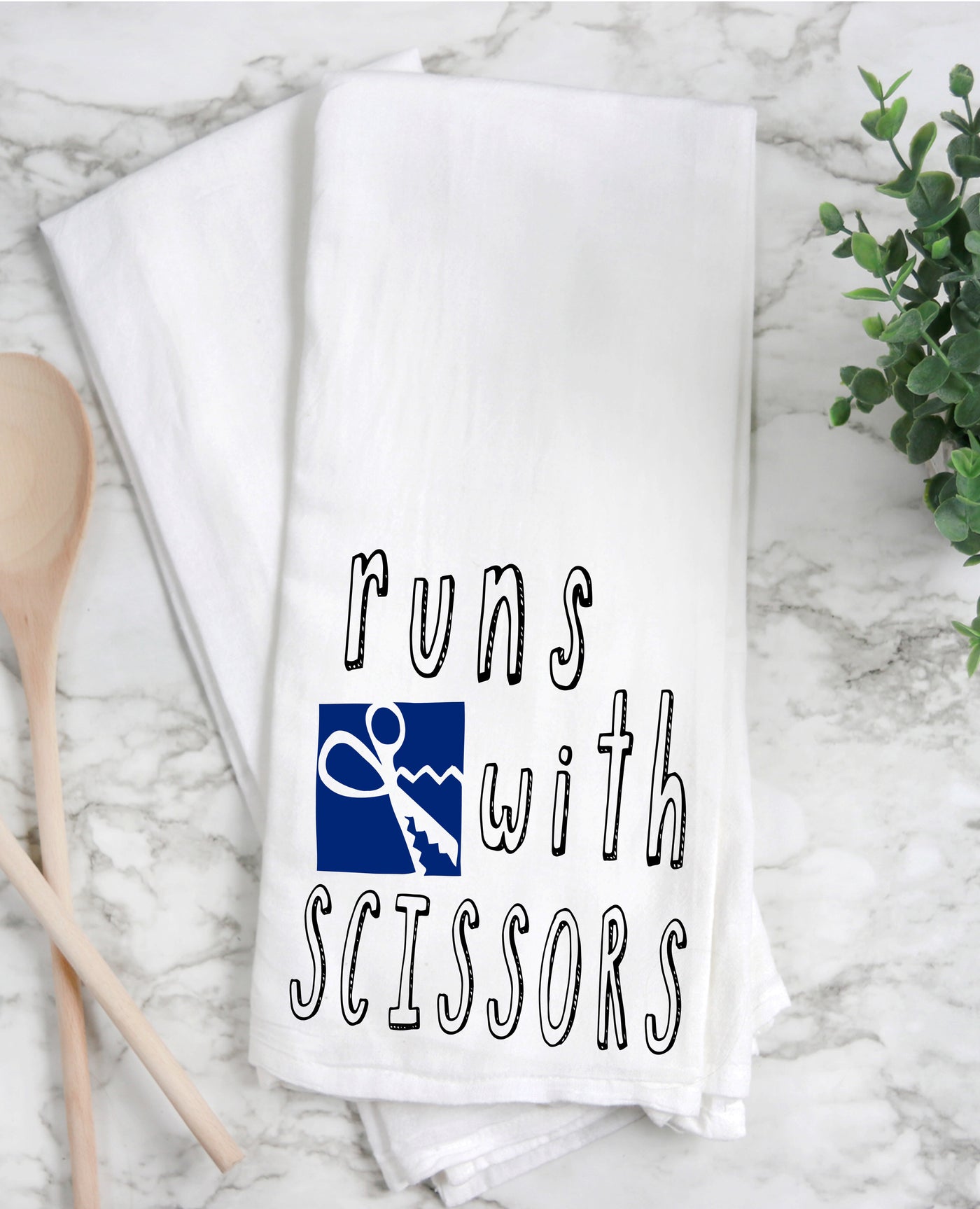 a white cotton kitchen towel with the words, "runs with scissors."