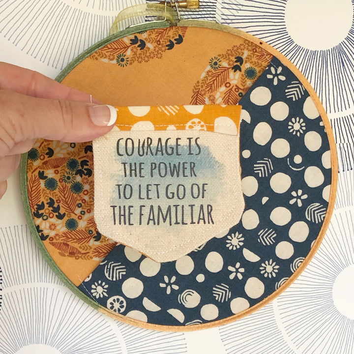 painted wooden hoop with fabric stretched and folded, creating a pocket.