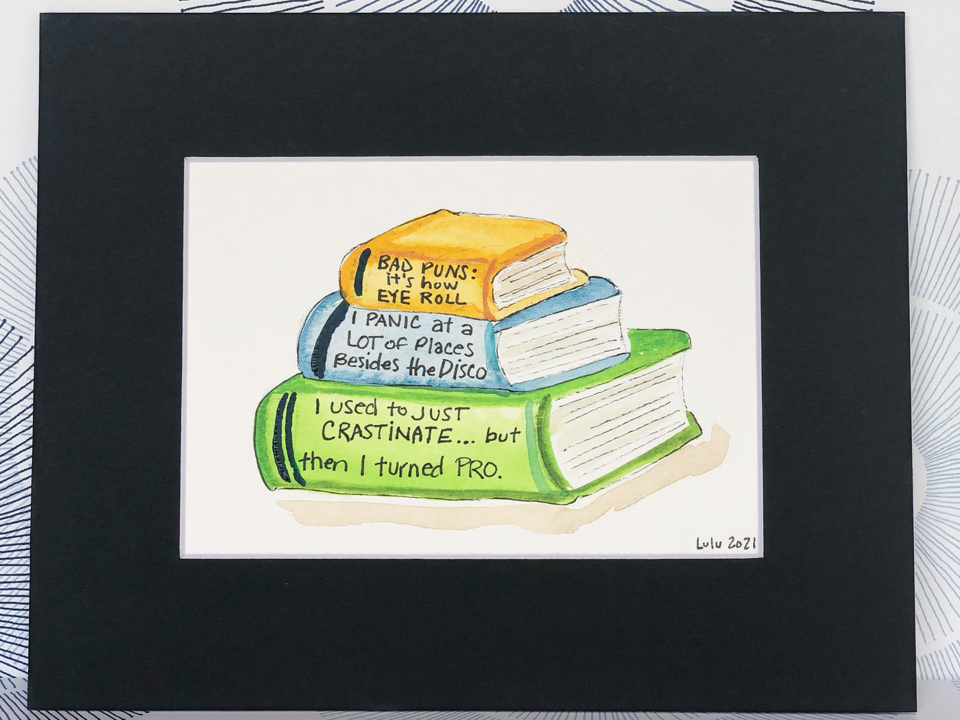 an original painted watercolor piece with three books in colors of burnt yellow, celery green and faded cerulean blue