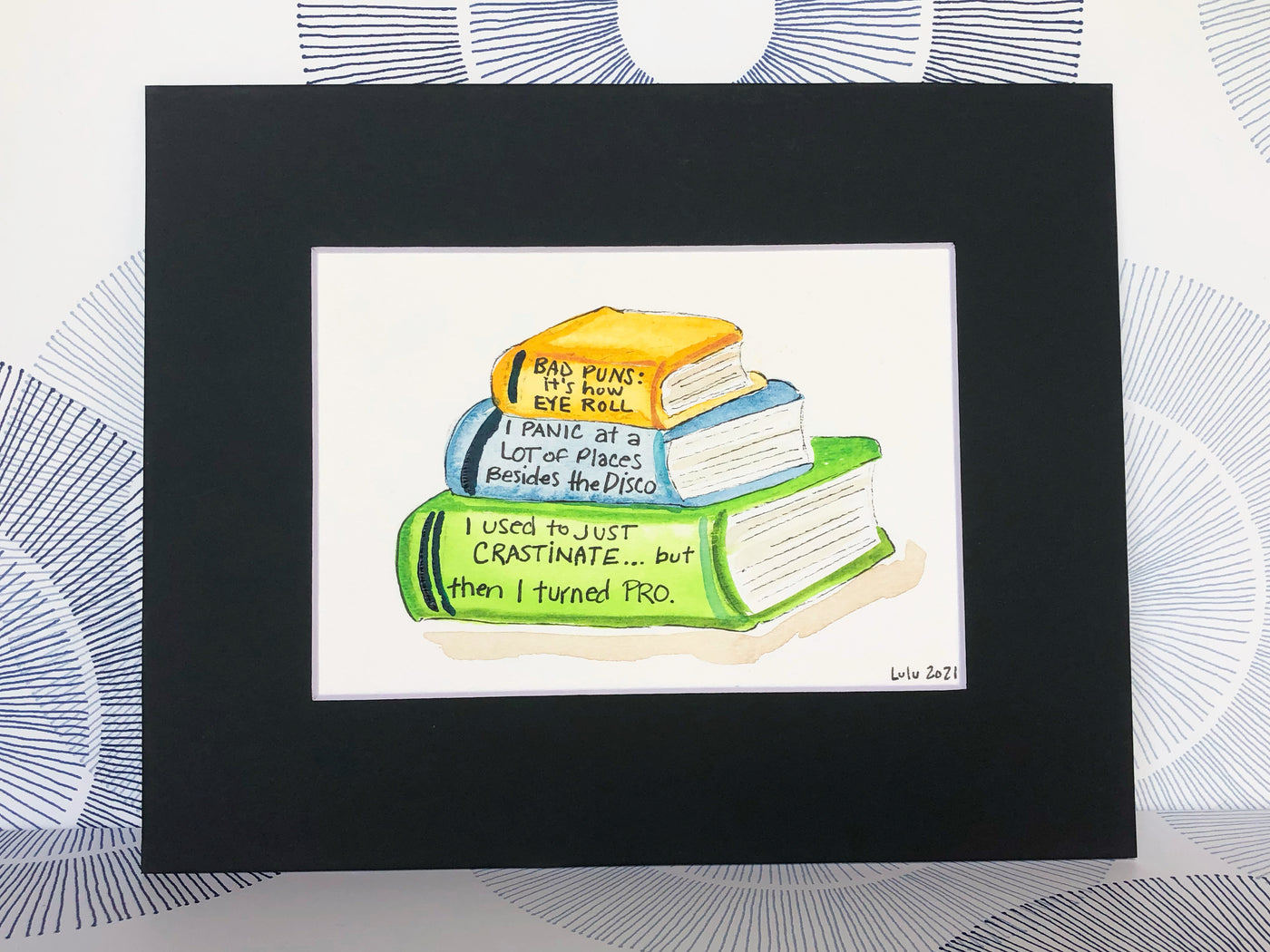 an original painted watercolor piece with three books in colors of burnt yellow, celery green and faded cerulean blue