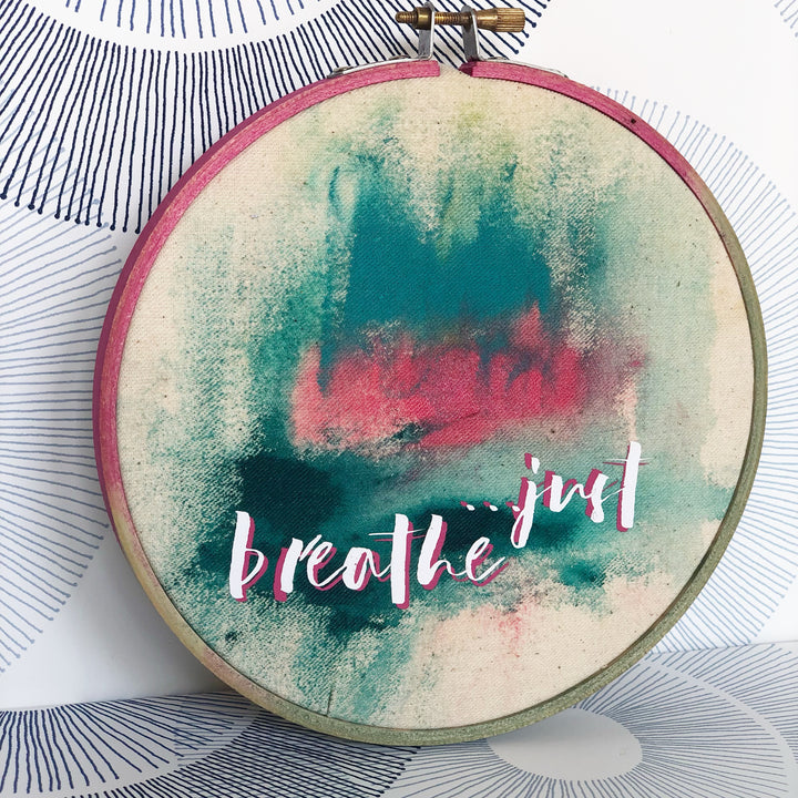 painted wooden hoop with fabric painting and the words, 'just breathe'