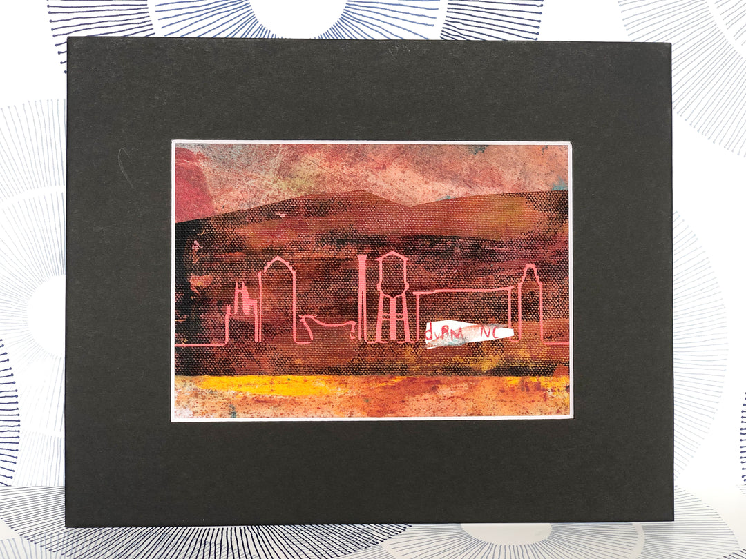 acrylic and watercolor painting on fabric, in colors of red, yellow and orange. the words, 'durm nc are printed in white, with a pink vinyl outline of the city