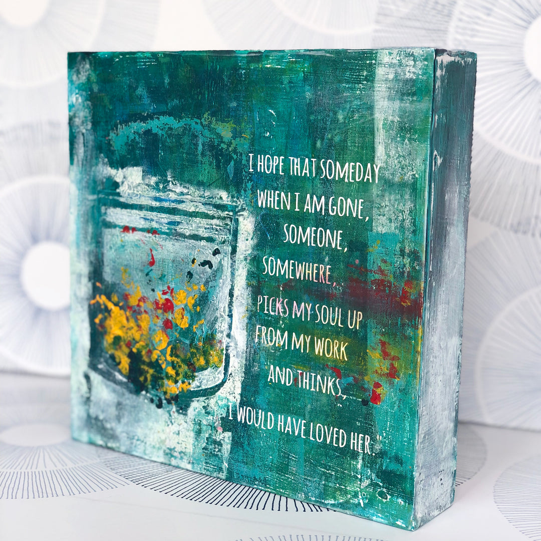 a painted wooden art piece with the words, "I hope that someday when i am gone, someone, somewhere, picks my soul up from my work and thinks...i would have loved her." Paints and inks are shades of green and teal, with accents of white, yellow and red.