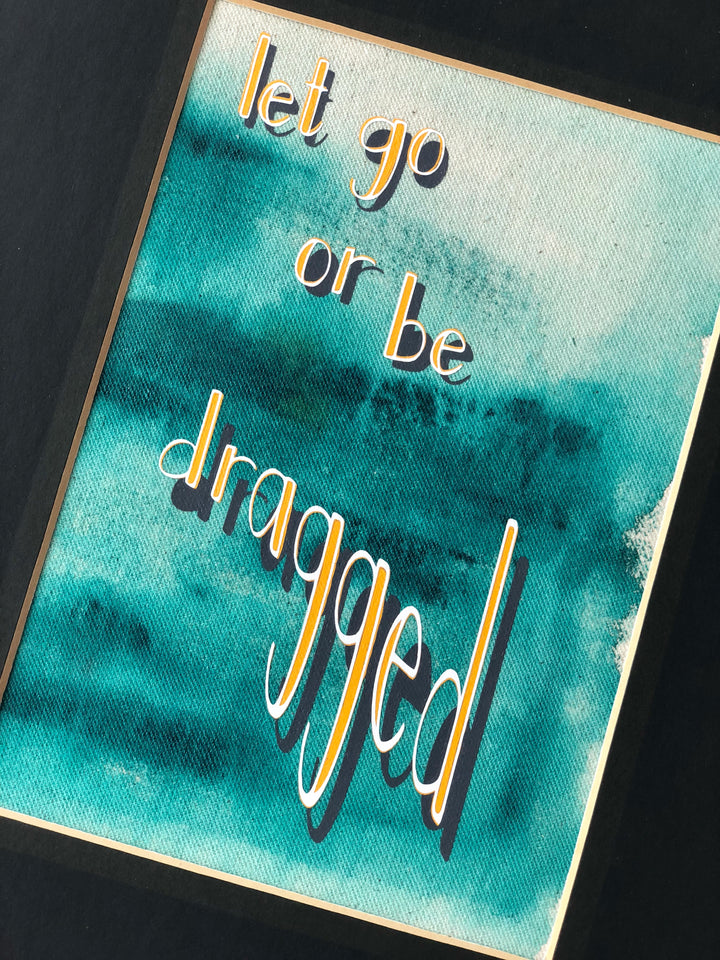 fabric print with green paint and the words, "let go or be dragged."