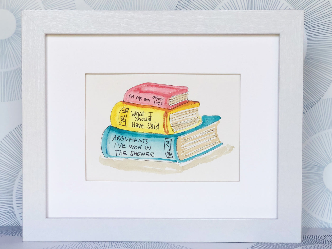 original watercolor painting of three books in red, yellow and blue