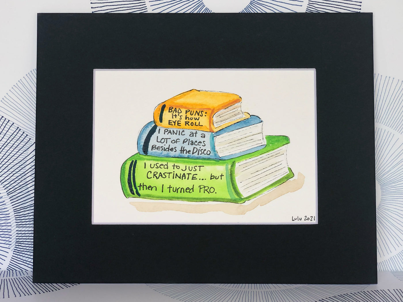 an original painted watercolor piece with three books in colors of burnt yellow, celery green and faded cerulean blue