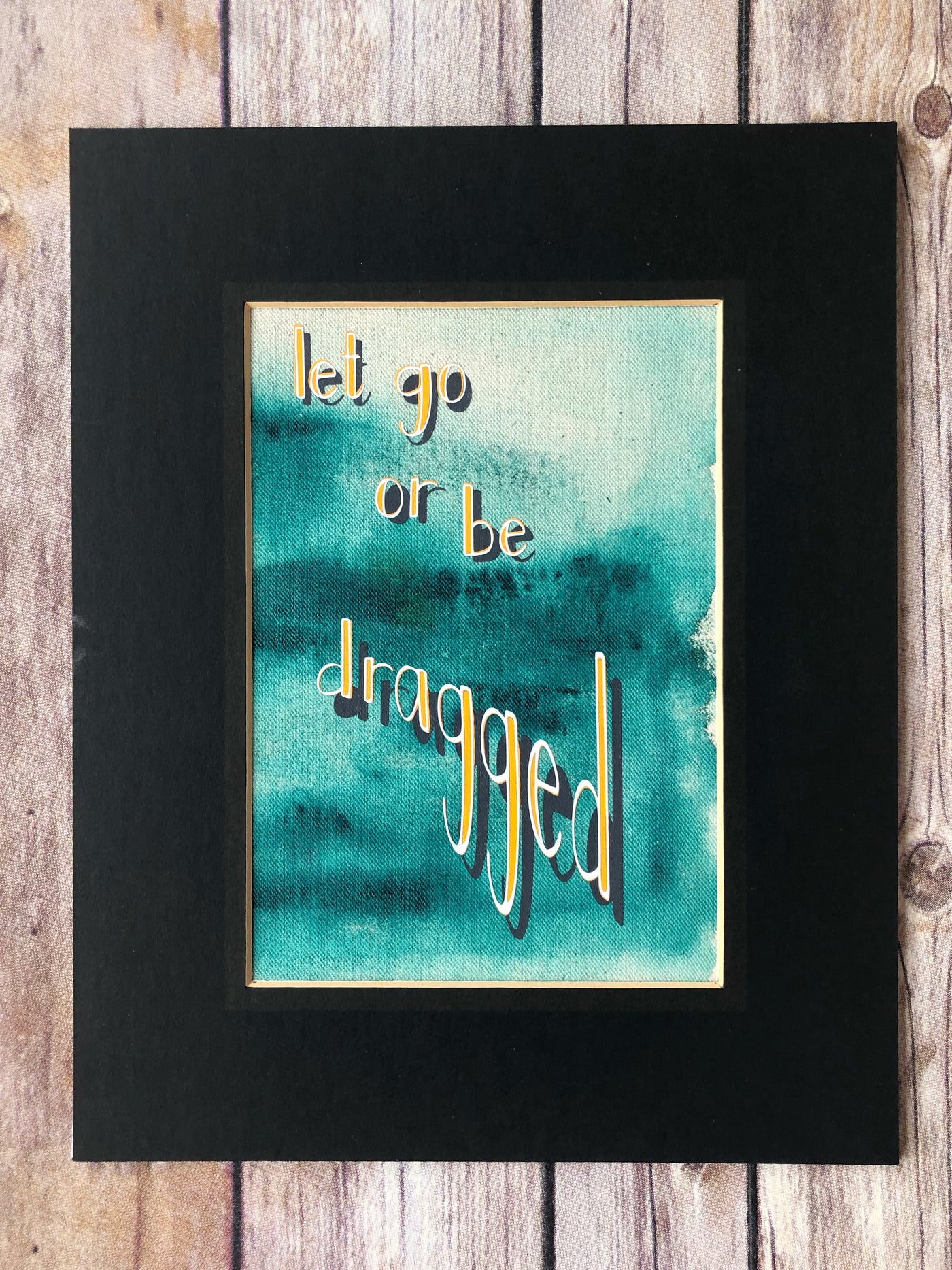 fabric print with green paint and the words, "let go or be dragged."