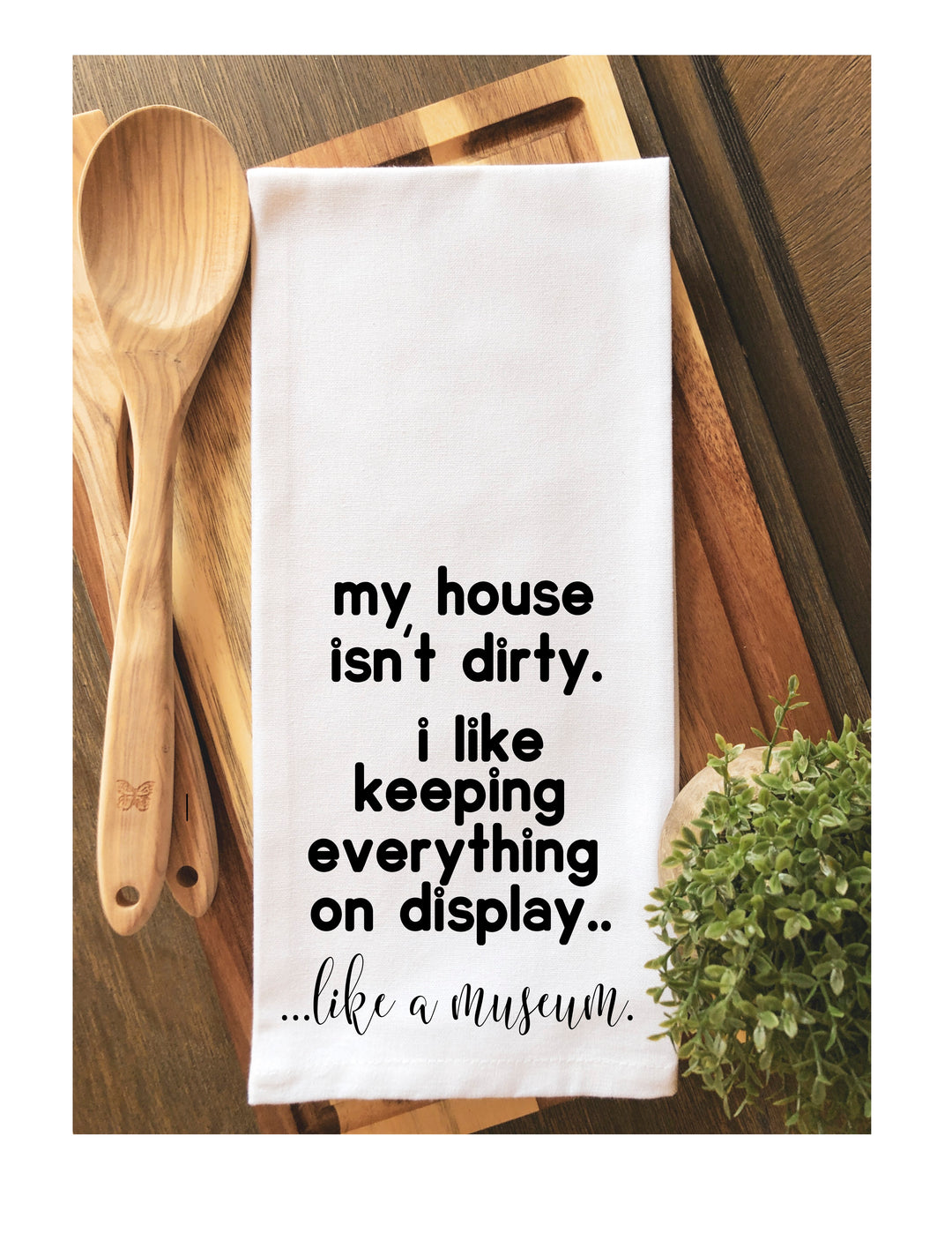 a white cotton kitchen towel with the words, "my house isn't dirty. I like keeping everything on display. like a museum."