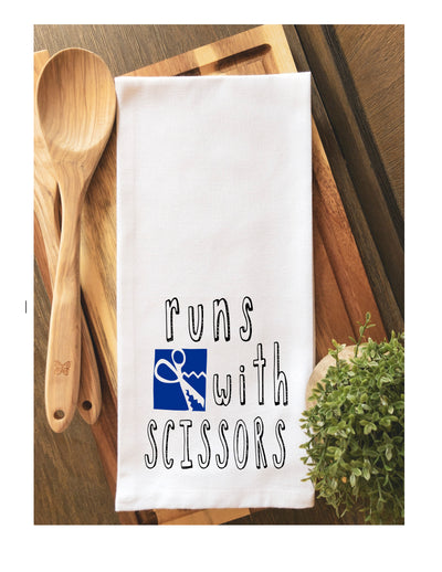 a white cotton kitchen towel with the words, "runs with scissors."